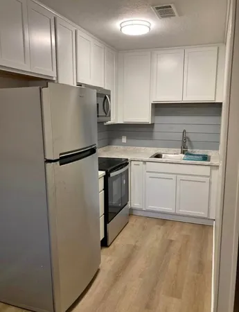 a kitchen with a refrigerator sink and cabinets