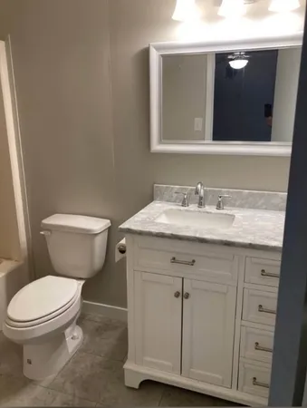 a bathroom with a granite countertop toilet sink and mirror