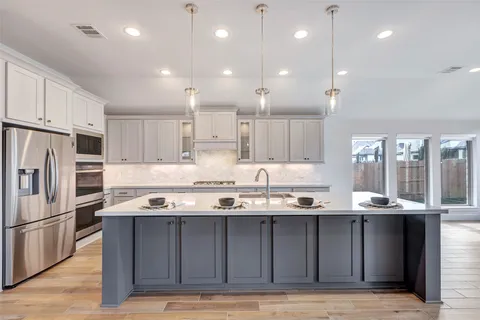 a kitchen with kitchen island stainless steel appliances a sink stove and refrigerator