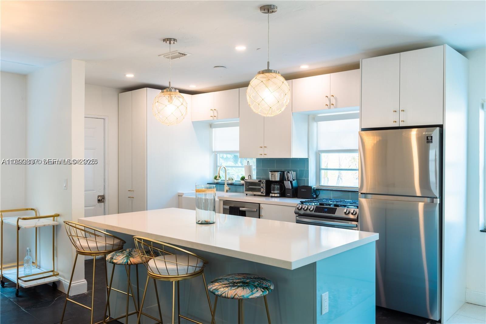 426 Northeast 26th Street, Unit 1 Miami, FL 33137 - Photo 2 of 23 a kitchen with kitchen island a table and a refrigerator