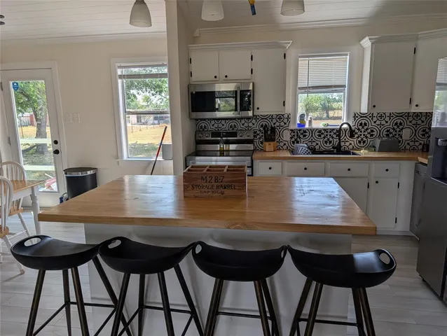 a view of kitchen island with stainless steel appliances refrigerator dining table and chairs