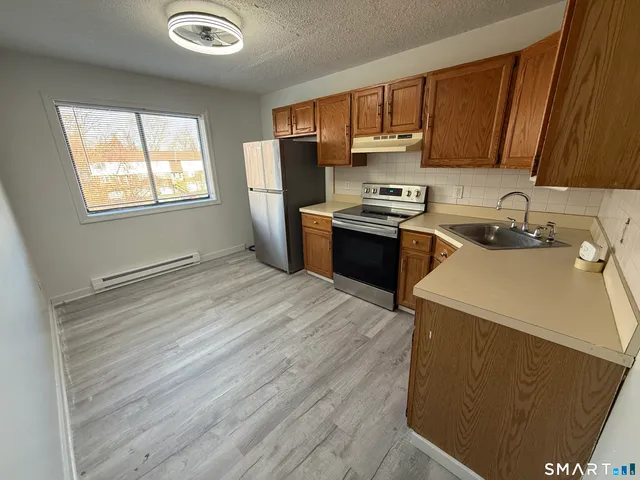 a kitchen with a sink a stove a refrigerator cabinets and a window