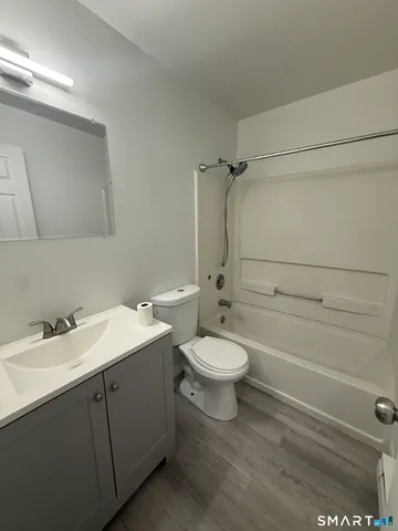 a bathroom with a toilet sink vanity granite and shower