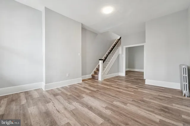 a view of an empty room with wooden floor and stairs