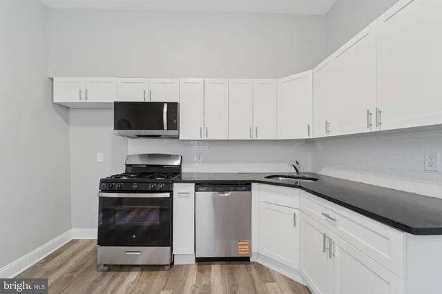 a kitchen with cabinets stainless steel appliances and a wooden floor