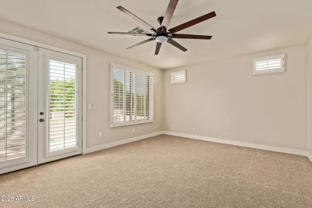 an empty room with windows and fan