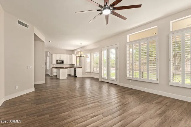 a view of an empty room with a window and wooden floor