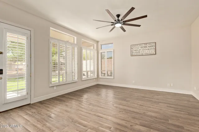 a view of an empty room with a window and wooden floor
