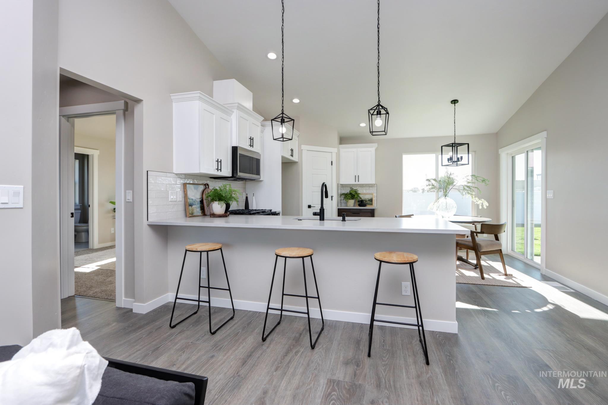 848 North 5th Street Nyssa, OR 97913 - Photo 4 of 49 Open-concept kitchen featuring an eat-at island, white cabinetry, stainless steel appliances, and wood-finish flooring