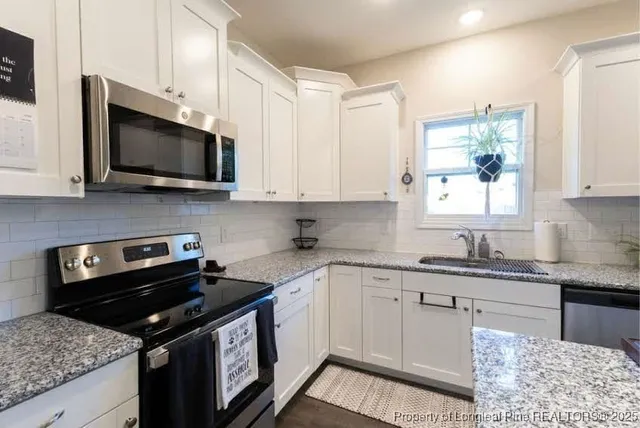 a kitchen with stainless steel appliances granite countertop a sink a stove a microwave and cabinets