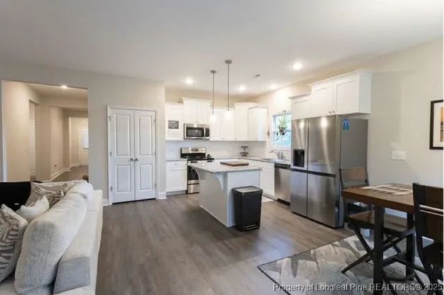 a kitchen with stainless steel appliances a refrigerator a stove a sink dishwasher and a refrigerator with wooden floor