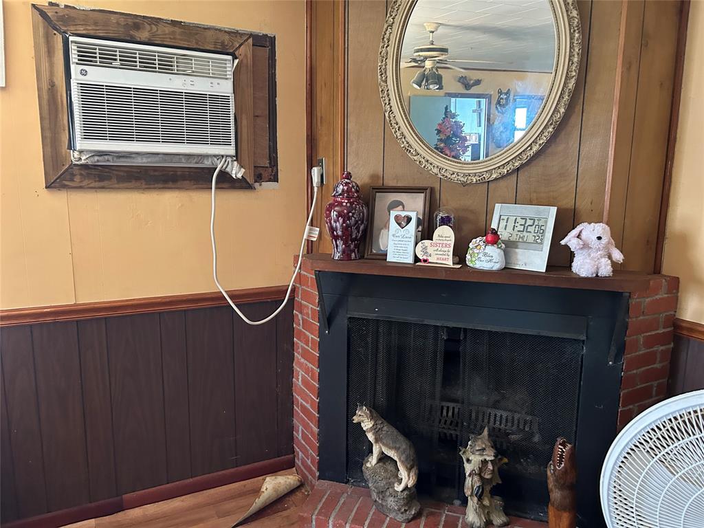 401 Ridge Row Many, LA 71449 - Photo 14 of 20 Detailed view of wooden walls, a wainscoted wall, a fireplace, wood finished floors, and an AC wall unit