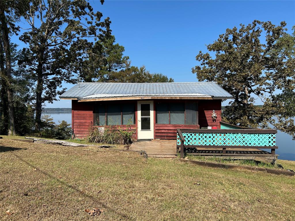 401 Ridge Row Many, LA 71449 - Photo 2 of 20 View of front of house with a front yard, a deck with water view, and a metal roof