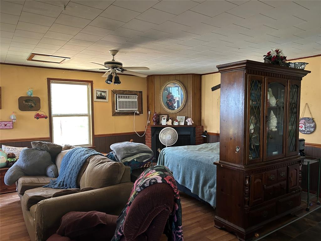 401 Ridge Row Many, LA 71449 - Photo 6 of 20 Bedroom featuring wooden walls, wainscoting, wood finished floors, a ceiling fan, and a wall unit AC