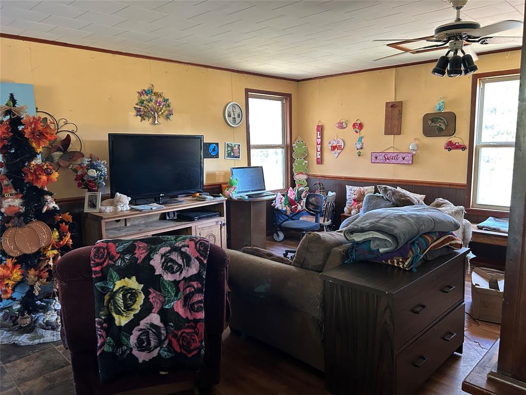 401 Ridge Row Many, LA 71449 - Photo 7 of 20 Living area featuring a wainscoted wall, a ceiling fan, wood finished floors, crown molding, and wooden walls