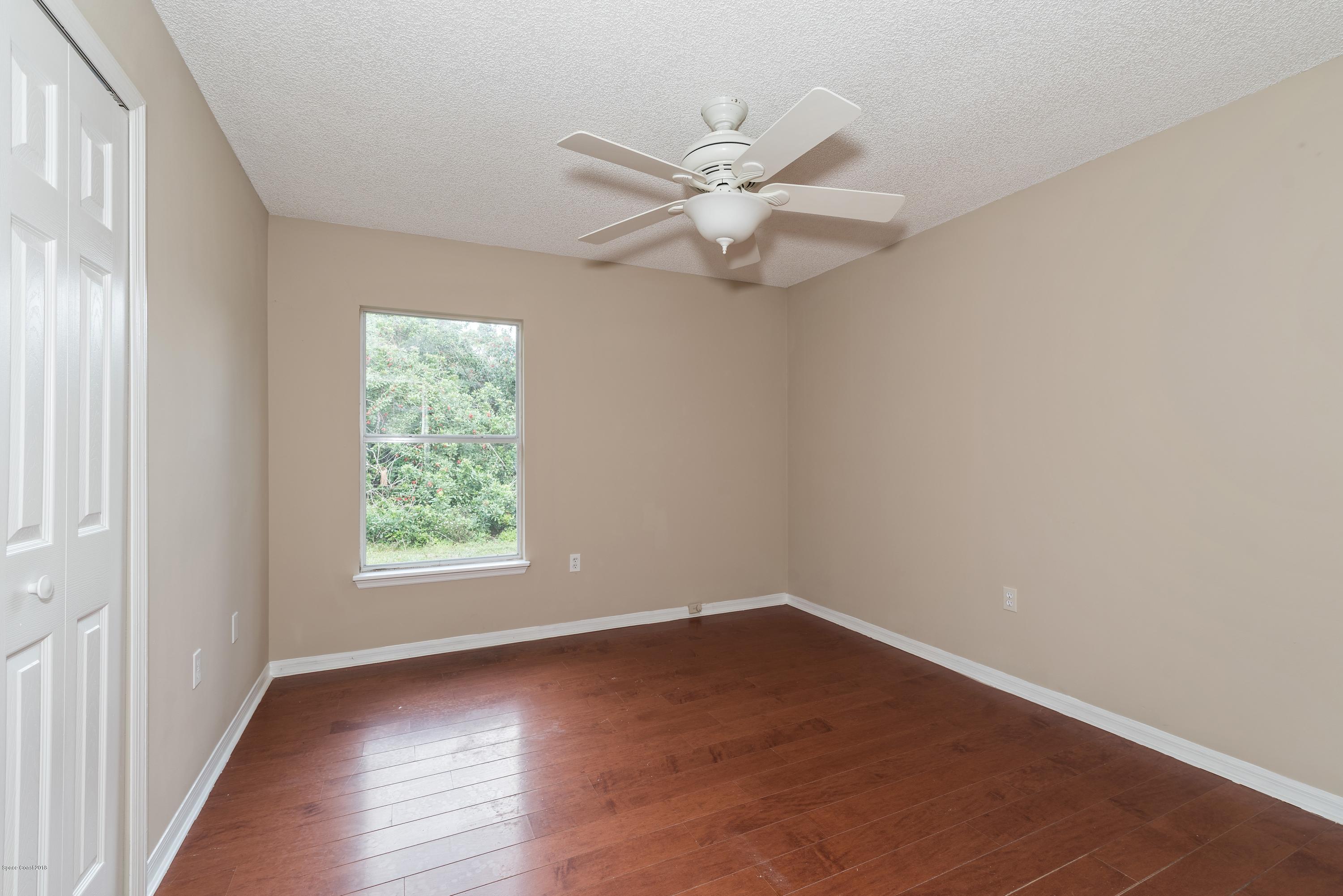 1208 Stadt Road Northwest Palm Bay, FL 32907 - Photo 15 of 24 an empty room with wooden floor fan and windows