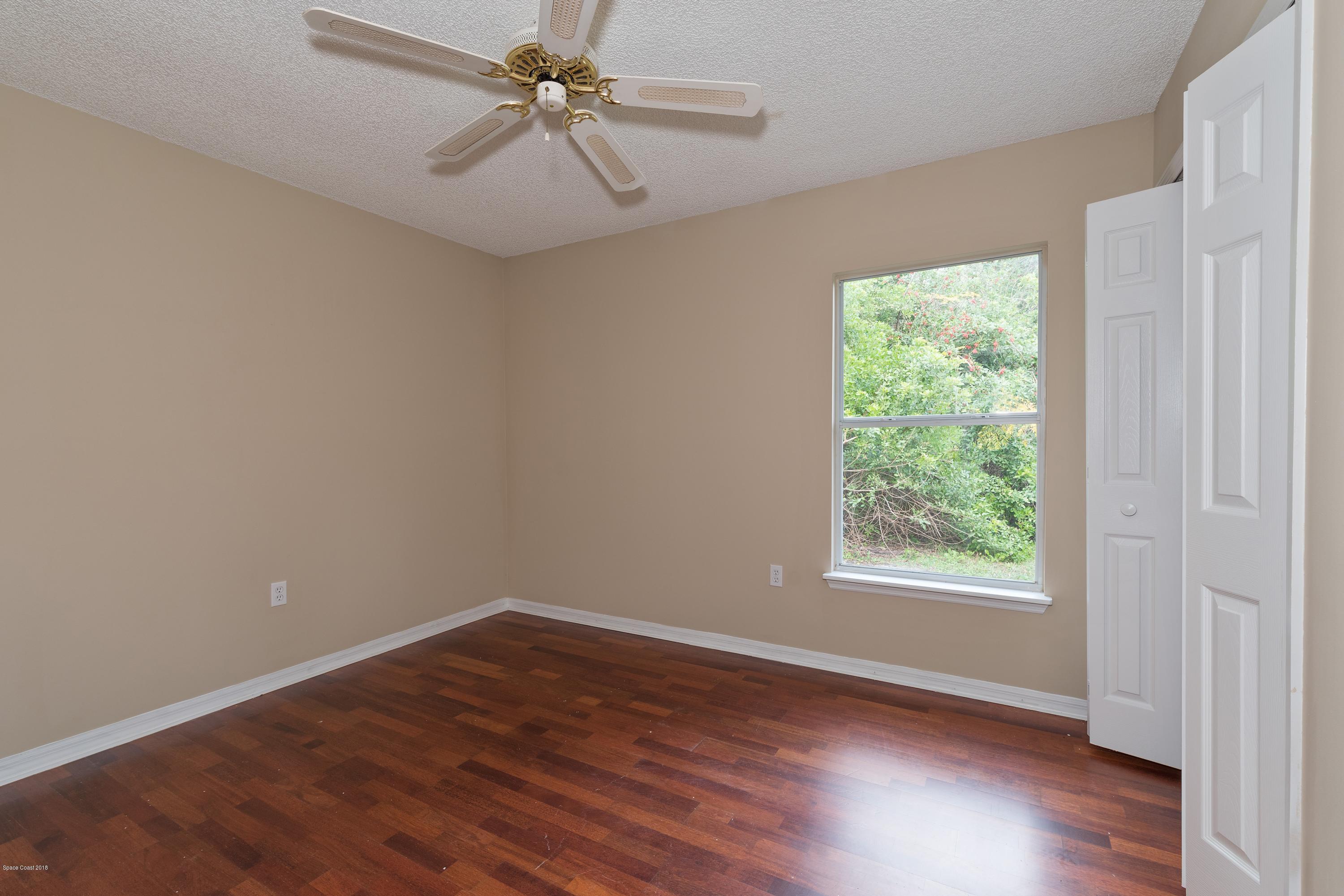 1208 Stadt Road Northwest Palm Bay, FL 32907 - Photo 16 of 24 an empty room with wooden floor fan and windows