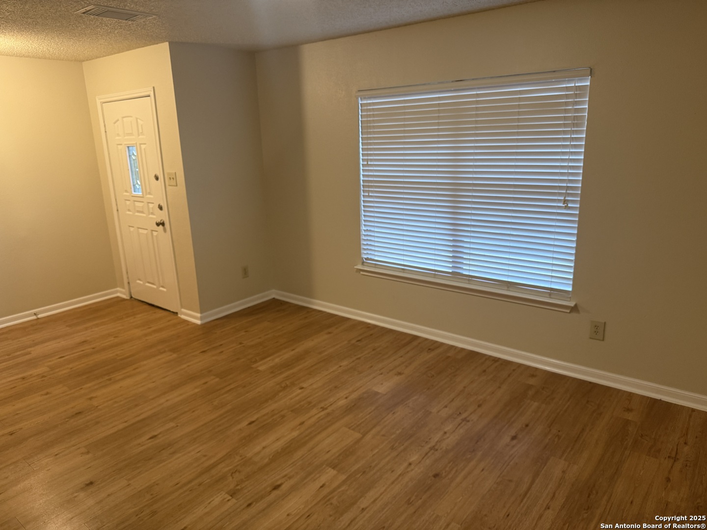 8022 Chestnut Clay Lane Converse, TX 78109 - Photo 2 of 21 a view of an empty room with wooden floor and a window