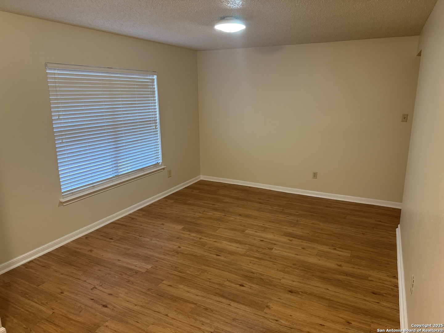 8022 Chestnut Clay Lane Converse, TX 78109 - Photo 3 of 21 a view of an empty room with wooden floor and a window