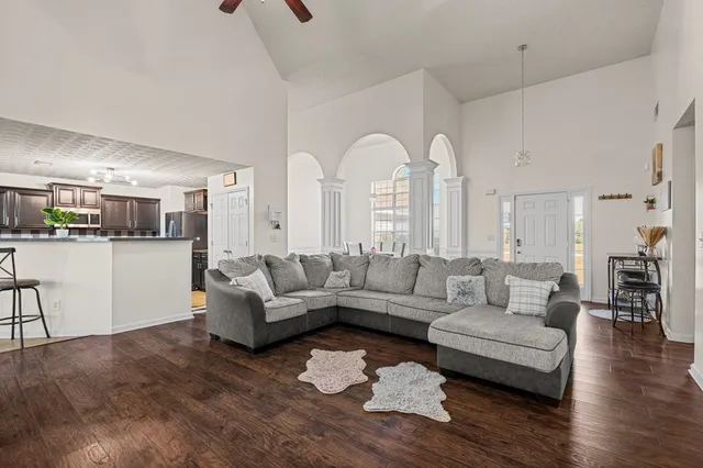 a living room with couches and kitchen view with wooden floor