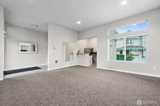 a view of empty room with a kitchen and a window