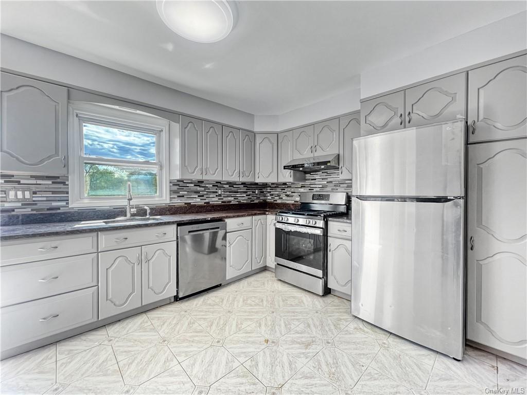 a kitchen with granite countertop a refrigerator sink stove and oven