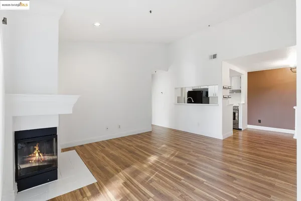 a view of a livingroom with wooden floor and a kitchen