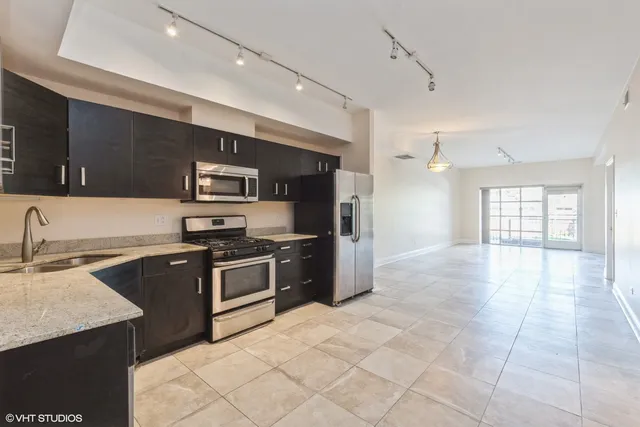 a kitchen with stainless steel appliances granite countertop a sink and stove top oven with wooden floor
