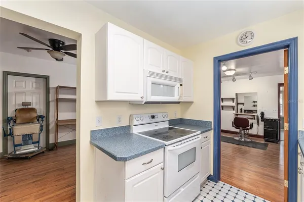 a kitchen with white cabinets and wooden floor