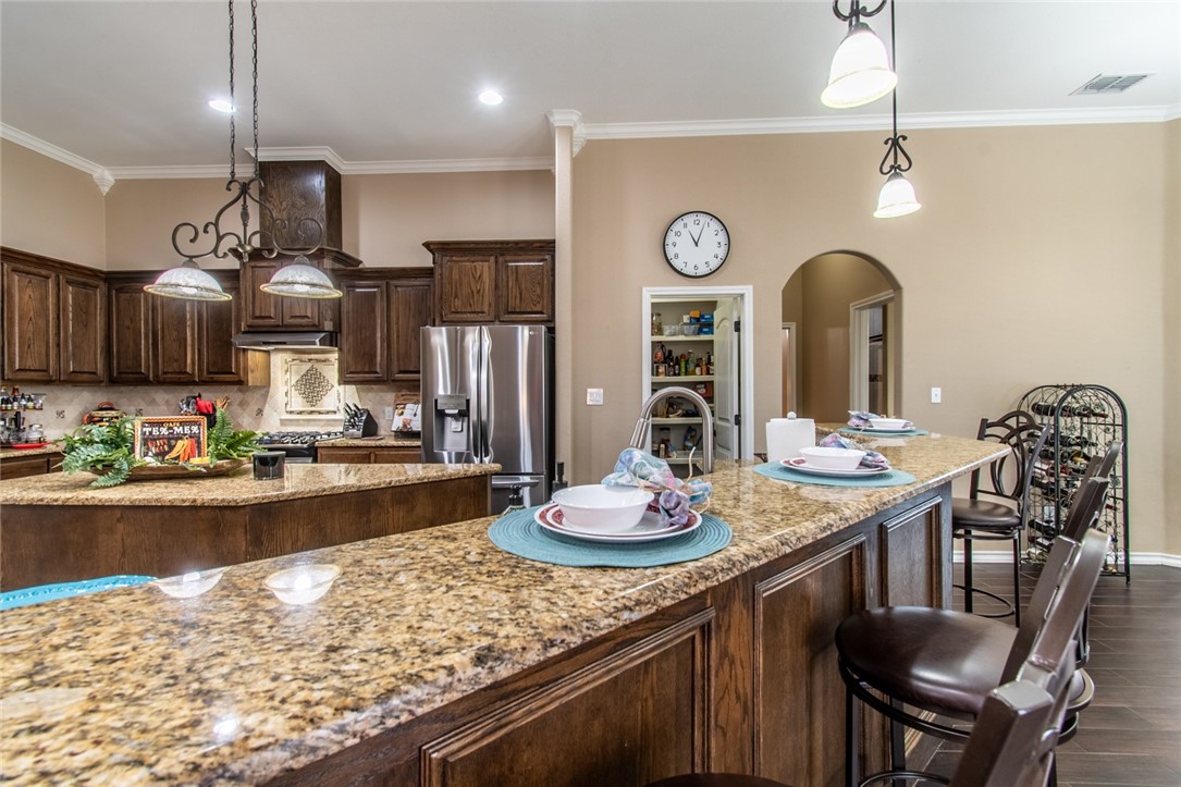 5309 Capernaum Court Corpus Christi, TX 78413 - Photo 22 of 40 a kitchen with stainless steel appliances granite countertop a sink a stove top oven a chimney and cabinets