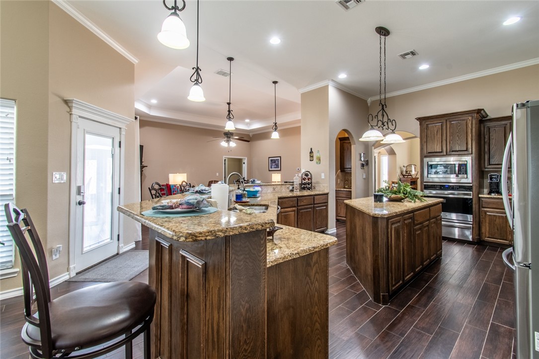 5309 Capernaum Court Corpus Christi, TX 78413 - Photo 23 of 40 a kitchen with stainless steel appliances kitchen island granite countertop a table chairs and a refrigerator
