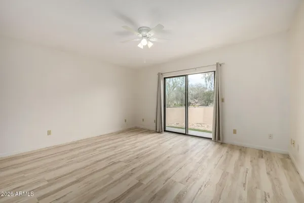 a view of an empty room with wooden floor and a window