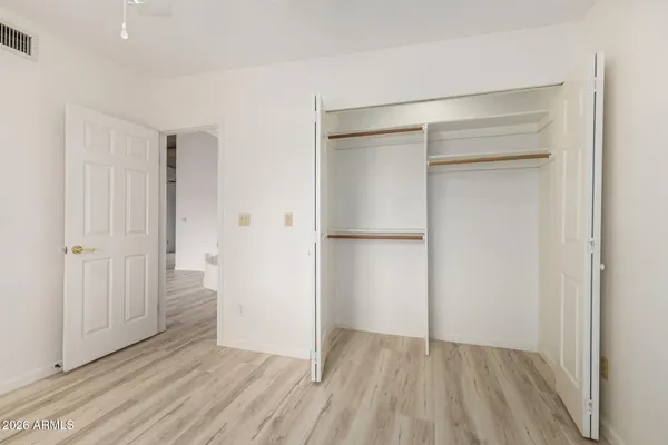 a view of an empty room with wooden floor and a hallway