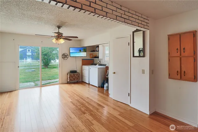 a view of a livingroom with a fireplace a ceiling fan and wooden floor