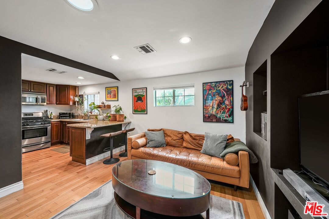 a living room with stainless steel appliances furniture and a flat screen tv