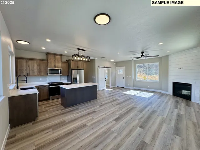 a large living room with stainless steel appliances kitchen island a large counter space a sink and a fireplace