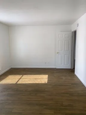a view of an empty room with wooden floor