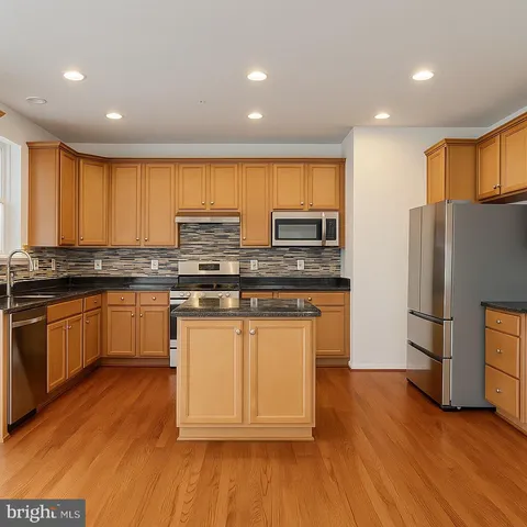 a kitchen with stainless steel appliances granite countertop a stove a sink and a refrigerator