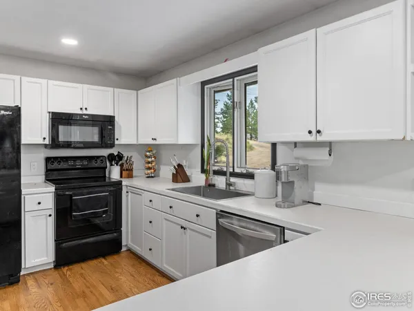 a kitchen with stainless steel appliances granite countertop a sink dishwasher a stove and a refrigerator with wooden floor