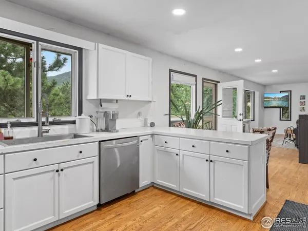 a kitchen with white cabinets and a large window