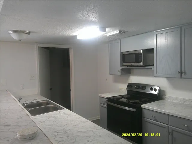 a kitchen with a sink and a stove top oven with wooden floor