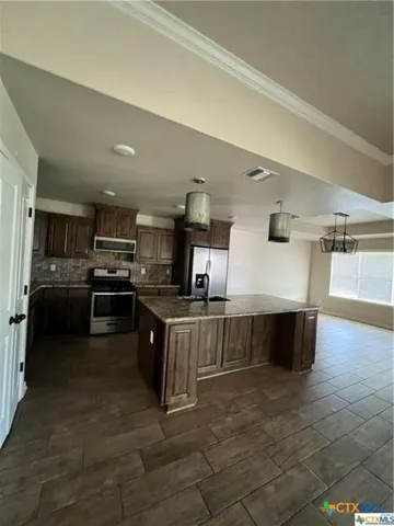 a large kitchen with stainless steel appliances kitchen island granite countertop a sink counter space and cabinets