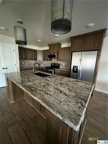 a kitchen with stainless steel appliances granite countertop a sink stove and refrigerator