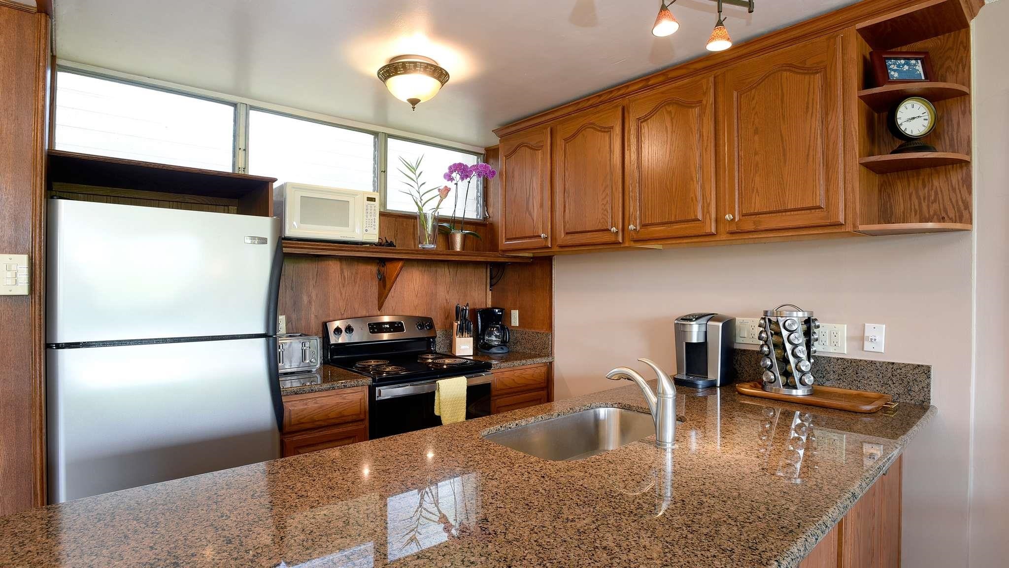 2619 South Kihei Road, Unit 309A Kihei, HI 96753 - Photo 13 of 41 a kitchen with stainless steel appliances granite countertop a refrigerator a stove and a sink with wooden floor