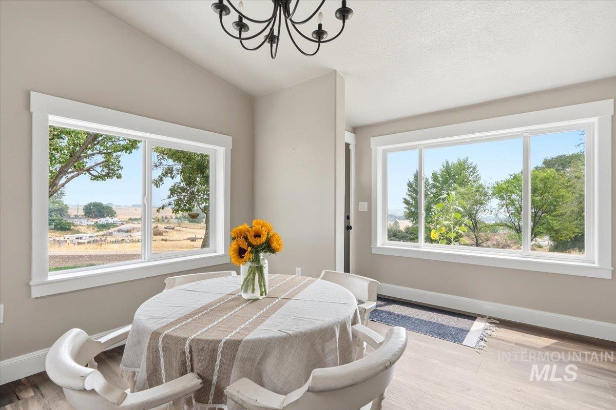 17114 Goodson Road Caldwell, ID 83607 - Photo 7 of 47 Light-filled dining area featuring expansive windows, wood-finish flooring, a contemporary black chandelier, and neutral wall tones