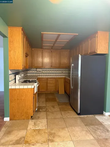 a kitchen with stainless steel appliances granite countertop a refrigerator a stove and a sink