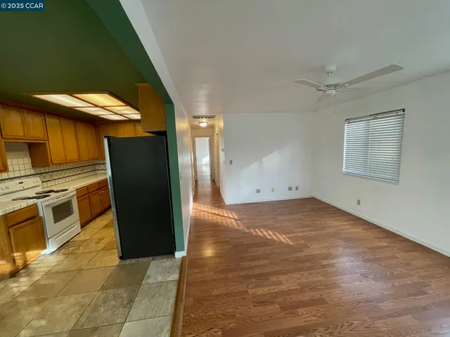a view of a refrigerator in kitchen and an empty room