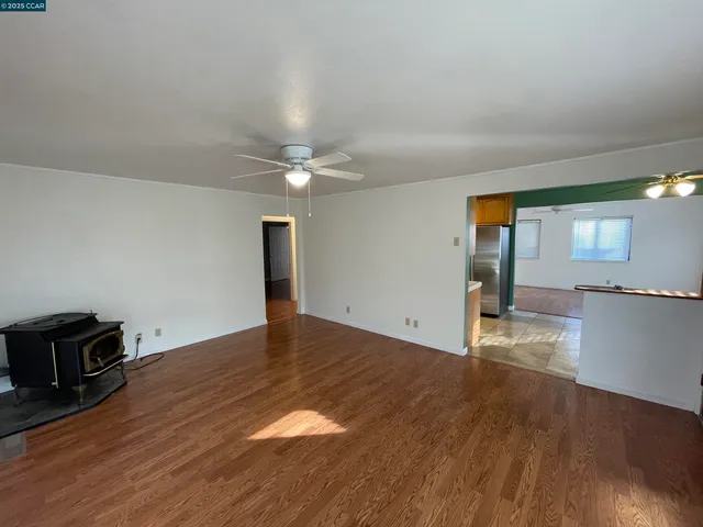 an empty room with wooden floor fan and windows
