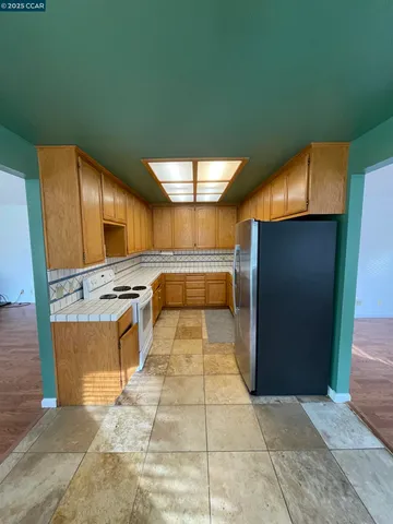 a kitchen with stainless steel appliances kitchen island granite countertop a refrigerator and a sink