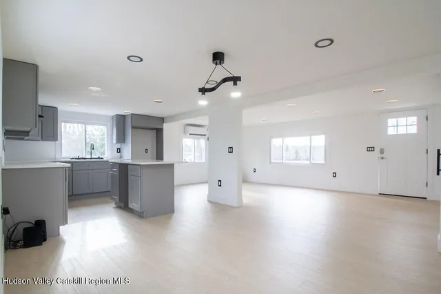 a view of an empty room and kitchen with a sink wooden floor and windows